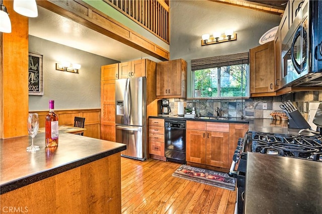 kitchen with appliances with stainless steel finishes, light wood-type flooring, dark countertops, decorative backsplash, and brown cabinetry