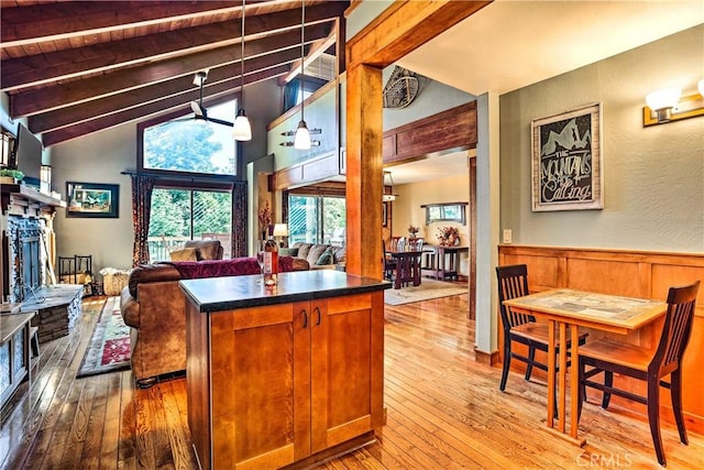 kitchen with wood-type flooring, dark countertops, a fireplace, open floor plan, and a wainscoted wall