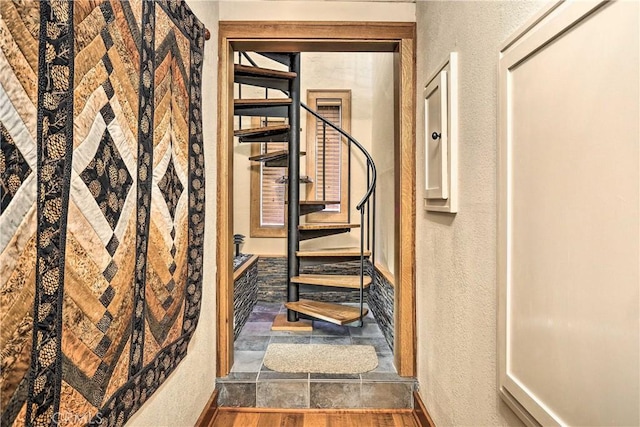 stairs with a textured wall, stone finish flooring, and baseboards