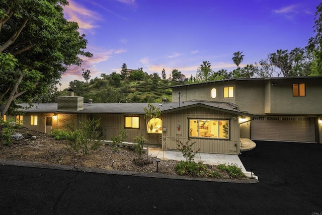 view of front of property featuring a chimney, asphalt driveway, and an attached garage