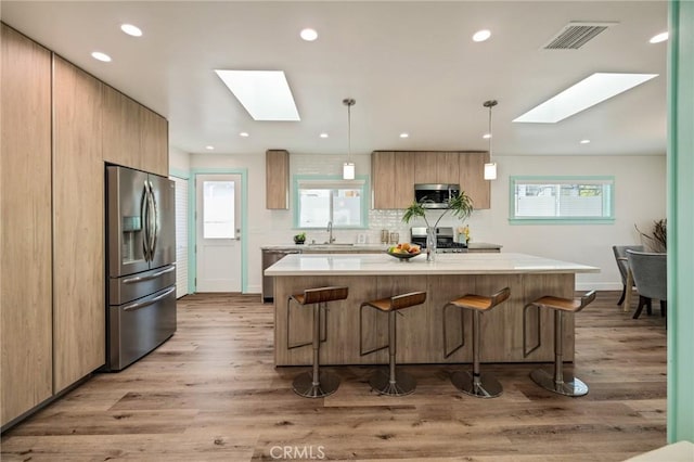 225 S Guadalupe Ave, Redondo Beach, CA 90277 - kitchen featuring a skylight, appliances with stainless steel finishes, light countertops, a kitchen breakfast bar, and recessed lighting