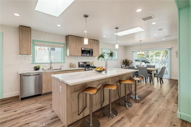 225 S Guadalupe Ave, Redondo Beach, CA 90277 - kitchen with stainless steel appliances, a skylight, a sink, a center island, and light wood-style floors