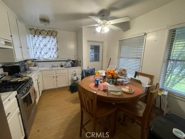 6705 Denny Ave, North Hollywood, CA 91606 - kitchen with gas range, black microwave, tile countertops, ventilation hood, and white cabinets
