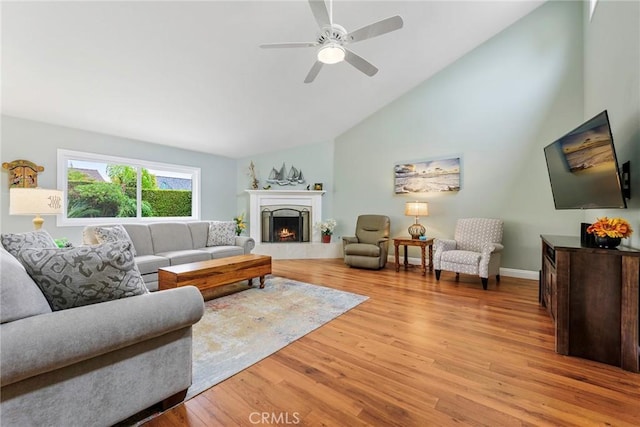 17152 Friml Ln, Huntington Beach, CA 92649 - living area with light wood-type flooring, a ceiling fan, a lit fireplace, high vaulted ceiling, and baseboards