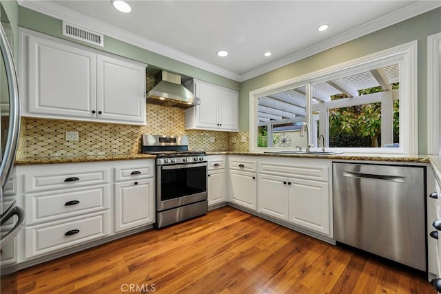 17152 Friml Ln, Huntington Beach, CA 92649 - kitchen with appliances with stainless steel finishes, wall chimney exhaust hood, light wood-type flooring, white cabinetry, and a sink