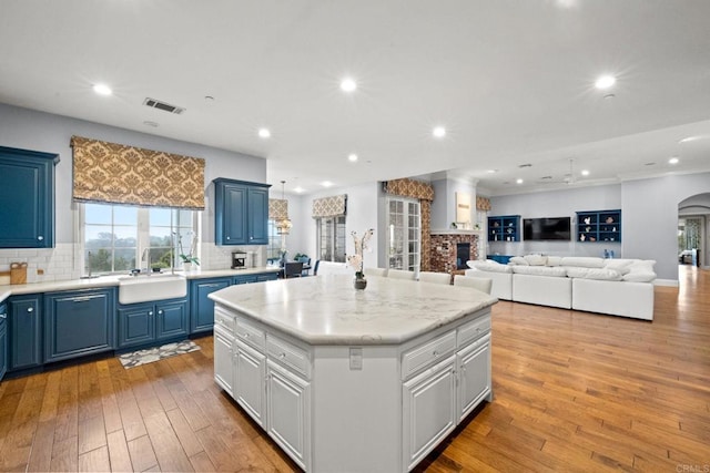 3401 Adams Run, Encinitas, CA 92024 - kitchen with blue cabinetry, tasteful backsplash, a center island, light wood-style flooring, and recessed lighting