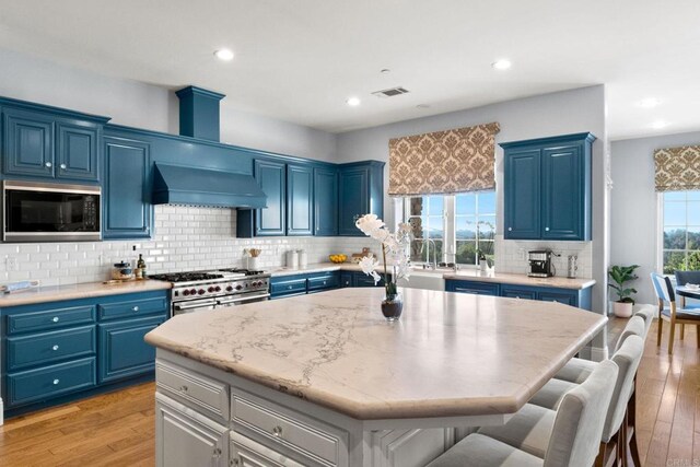 3401 Adams Run, Encinitas, CA 92024 - kitchen featuring black microwave, premium range hood, blue cabinets, a breakfast bar area, and recessed lighting