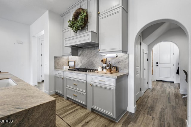 4173 Caribbean St, Oxnard, CA 93035 - kitchen with gray cabinetry, wood finished floors, stainless steel gas cooktop, backsplash, and arched walkways
