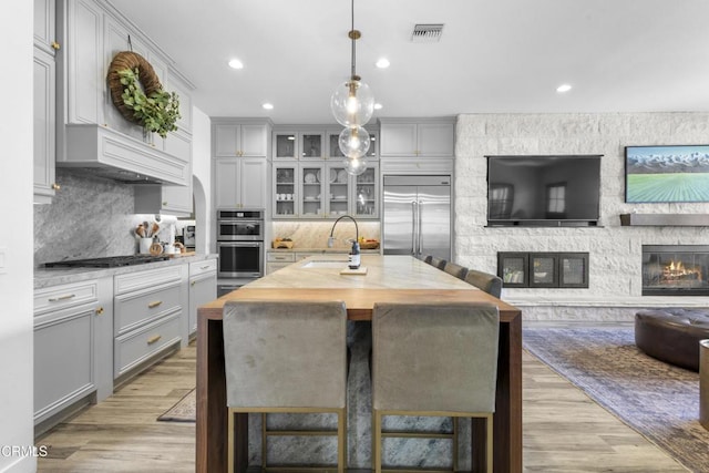 4173 Caribbean St, Oxnard, CA 93035 - kitchen with appliances with stainless steel finishes, gray cabinetry, open floor plan, a sink, and a fireplace