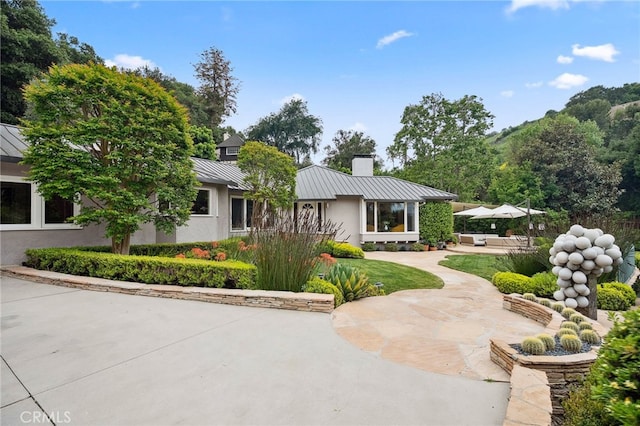 3818 Hollyline Ave, Sherman Oaks, CA 91423 - view of front of house with a standing seam roof, a chimney, a patio area, and metal roof