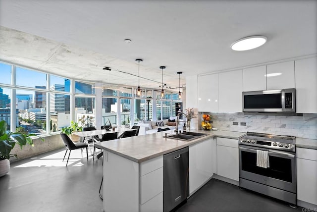 1080 Park Blvd Unit 701, San Diego, CA 92101 - kitchen featuring stainless steel appliances, a sink, a peninsula, decorative backsplash, and white cabinetry