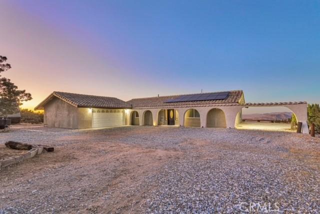 25624 Castlerock Rd, Apple Valley, CA 92308 - view of front facade featuring an attached garage, driveway, solar panels, a tiled roof, and stucco siding