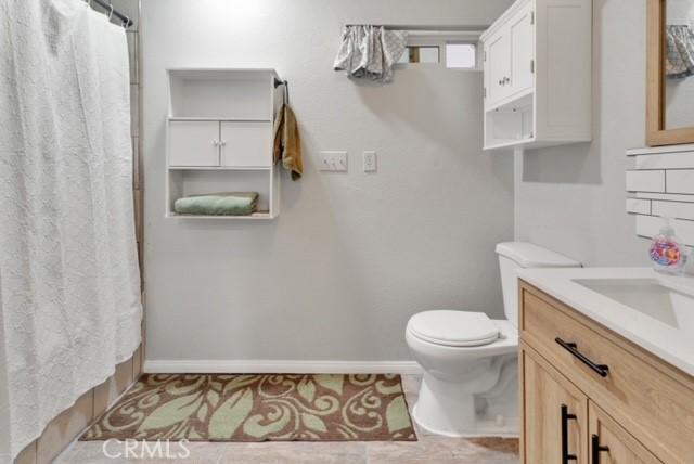 25624 Castlerock Rd, Apple Valley, CA 92308 - full bathroom featuring toilet, vanity, a shower with curtain, and baseboards