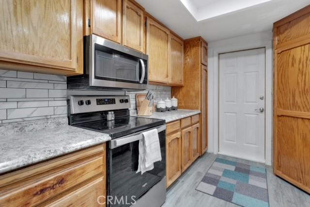 25624 Castlerock Rd, Apple Valley, CA 92308 - kitchen with stainless steel appliances, light countertops, tasteful backsplash, and light wood-type flooring