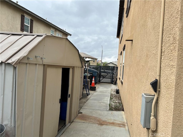view of side of property featuring a storage shed, stucco siding, an outbuilding, and fence
