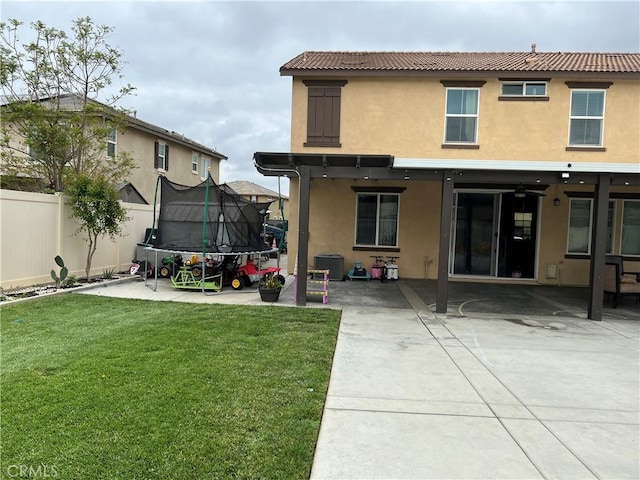 back of house featuring a trampoline, stucco siding, a patio area, a tile roof, and central AC