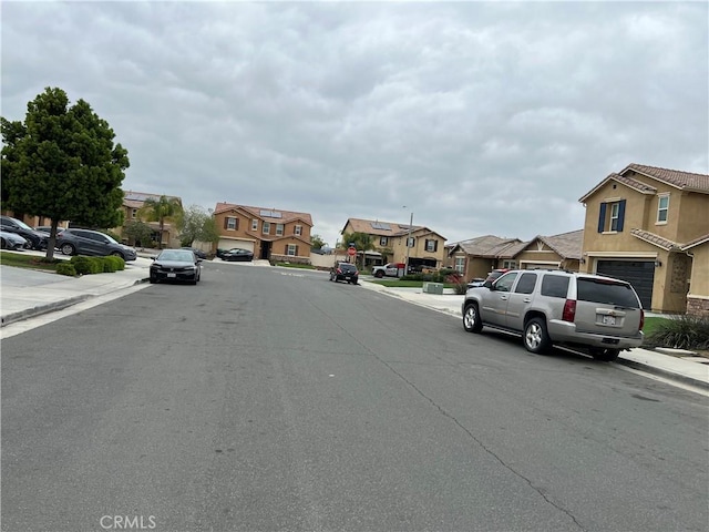 view of asphalt road featuring a residential view, sidewalks, and curbs