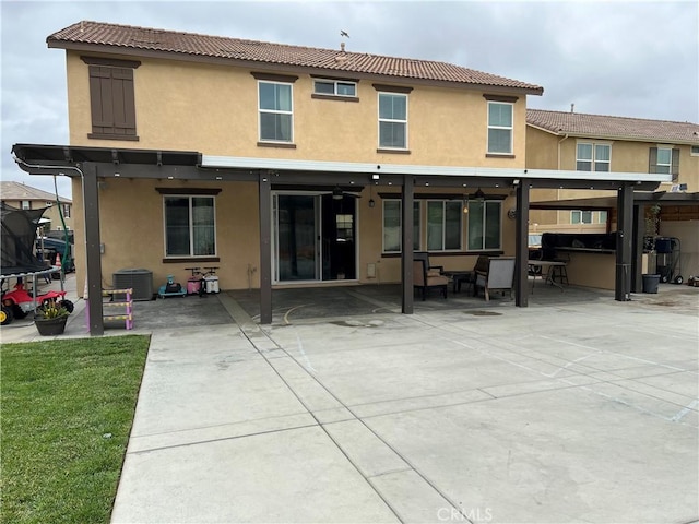 back of property featuring stucco siding, cooling unit, a patio area, and a trampoline