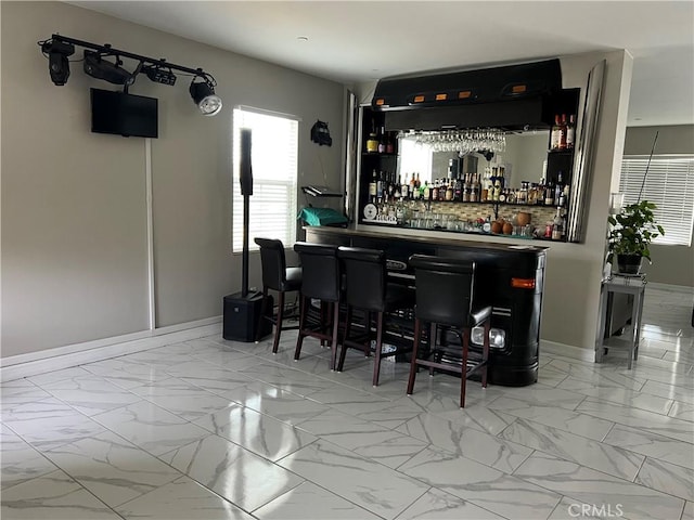 indoor dry bar with marble look tiles and baseboards