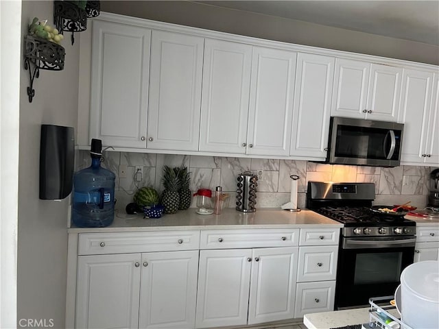 kitchen with stainless steel appliances, white cabinetry, decorative backsplash, and light countertops