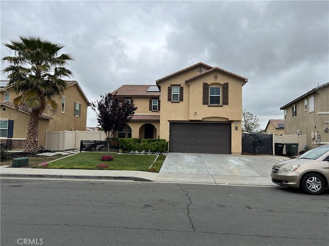 mediterranean / spanish house with stucco siding, a garage, driveway, a tiled roof, and a gate