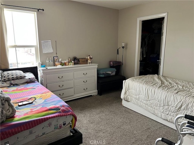 bedroom with multiple windows, dark carpet, and a spacious closet