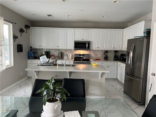 kitchen featuring stainless steel appliances, light marble finish floors, a sink, light countertops, and recessed lighting