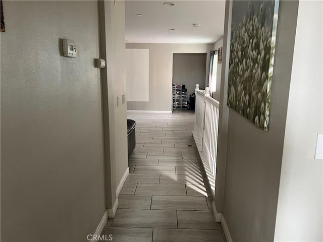 hallway featuring baseboards and wood finish floors