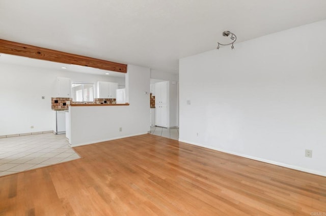 unfurnished living room with light wood-style flooring, baseboards, and beam ceiling