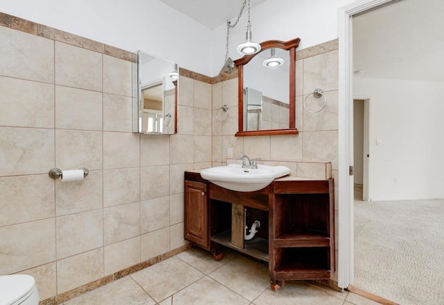 bathroom with tile walls, toilet, vanity, and tile patterned floors