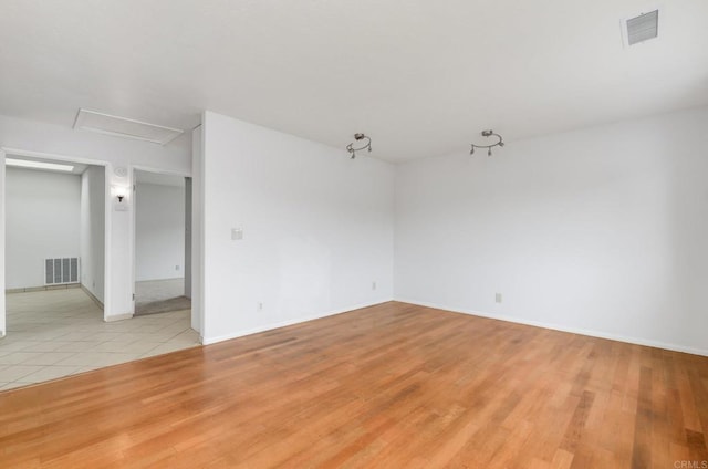 empty room with attic access, light wood-style flooring, and baseboards