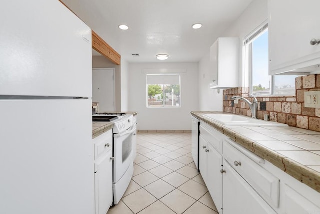 kitchen with white appliances, a sink, tile counters, white cabinetry, and recessed lighting