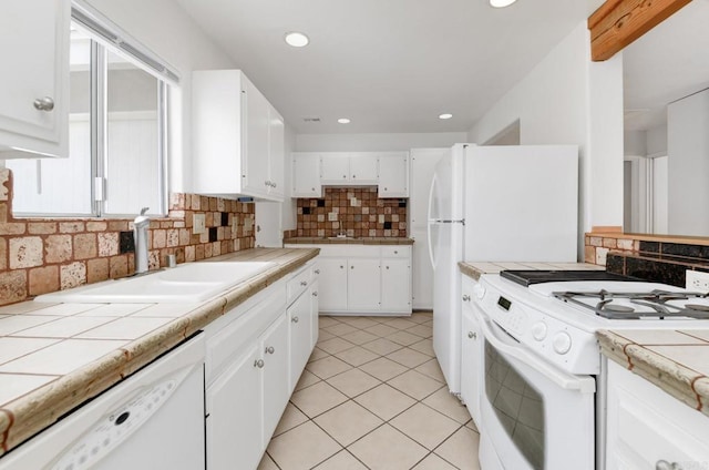 kitchen with white appliances, a sink, tile countertops, tasteful backsplash, and white cabinetry