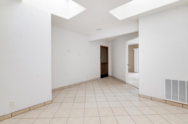 empty room featuring a skylight and baseboards