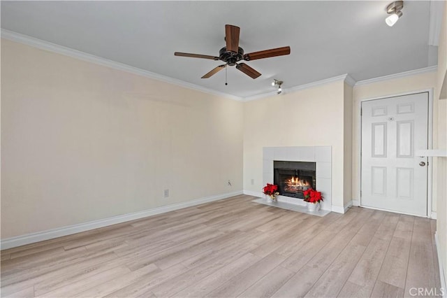 unfurnished living room featuring a ceiling fan, crown molding, light wood-style flooring, a tile fireplace, and baseboards