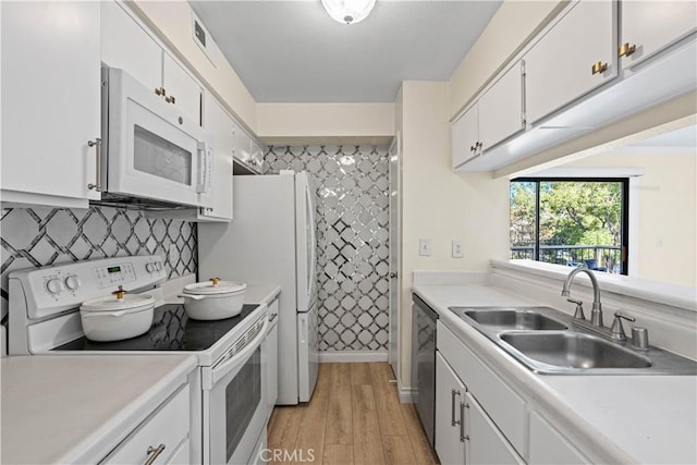 kitchen with white appliances, a sink, white cabinetry, light countertops, and light wood-type flooring