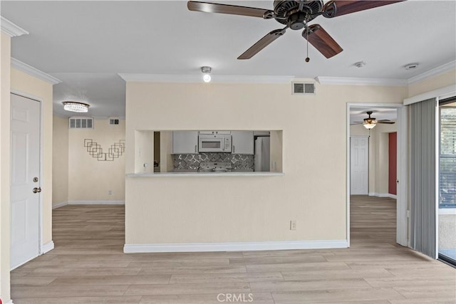unfurnished living room featuring a ceiling fan, crown molding, light wood-style flooring, and baseboards