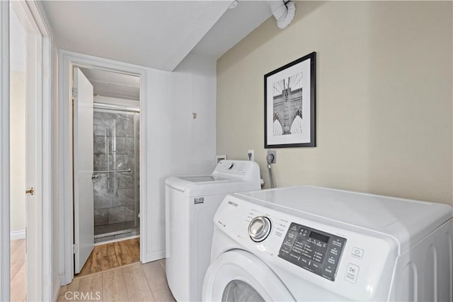 laundry area with washer and dryer and light wood-style flooring