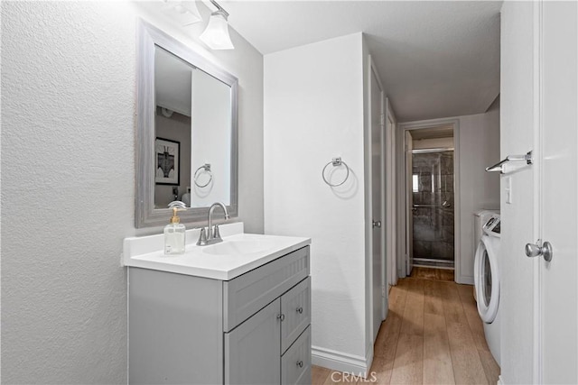 bathroom with washer and dryer, wood finished floors, vanity, and a textured wall