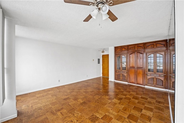 empty room with a ceiling fan, a textured ceiling, and baseboards