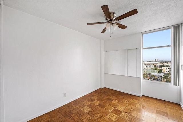 empty room with a ceiling fan and baseboards