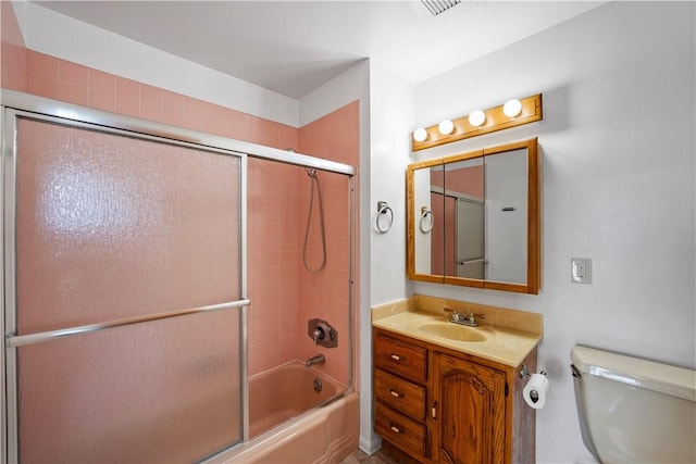 bathroom with toilet, shower / bath combination with glass door, and vanity