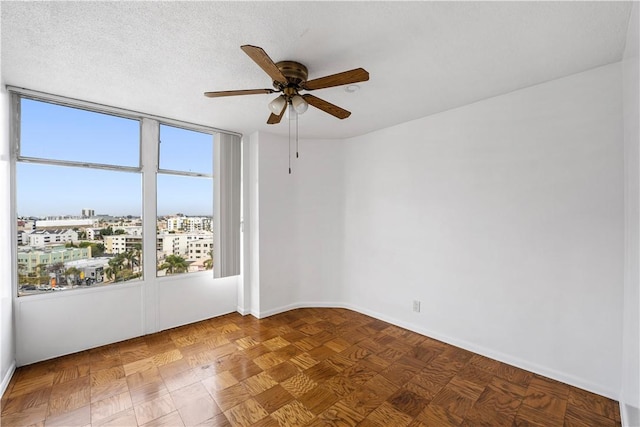 spare room with healthy amount of natural light, a ceiling fan, a view of city, and baseboards