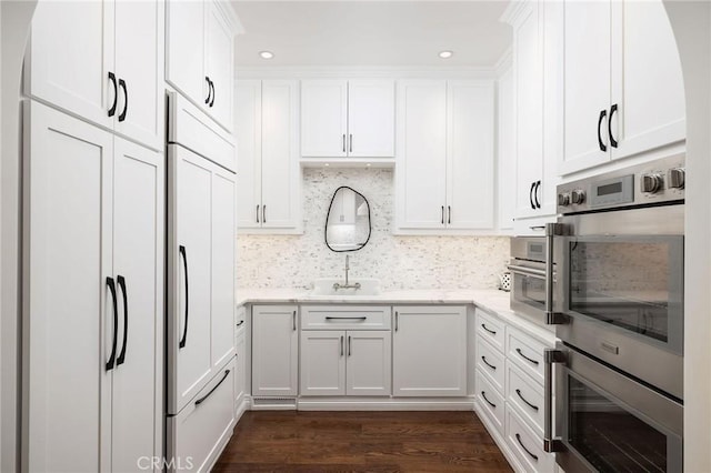 427 10th St, Huntington Beach, CA 92648 - kitchen with stainless steel double oven, white cabinetry, dark wood-style flooring, paneled built in fridge, and a sink