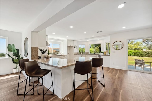 529 Manzanita Rd, Redlands, CA 92373 - kitchen featuring a peninsula, light stone counters, white cabinets, a kitchen breakfast bar, and a sink