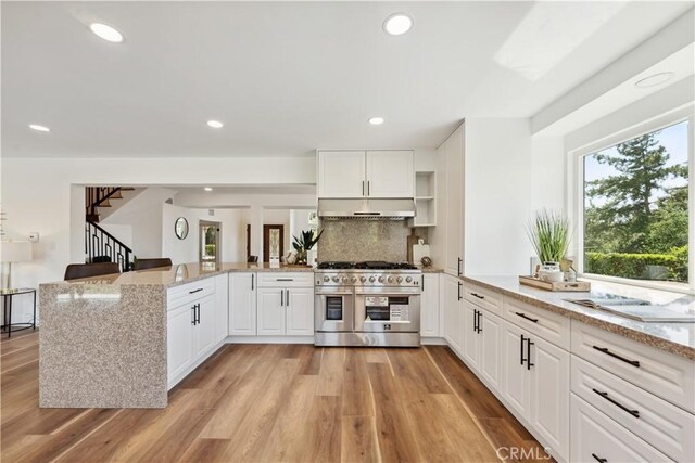 529 Manzanita Rd, Redlands, CA 92373 - kitchen with range with two ovens, a peninsula, backsplash, under cabinet range hood, and light stone counters