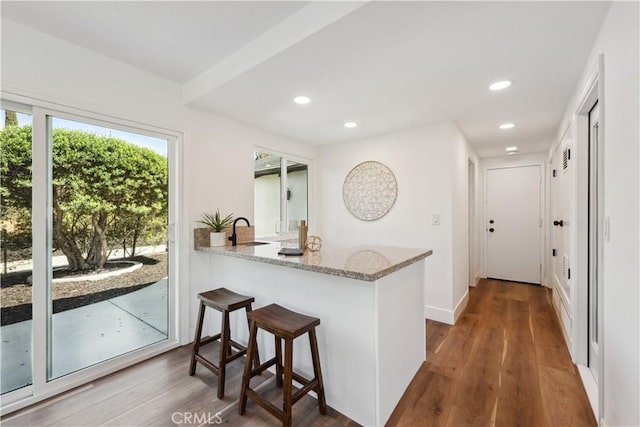 529 Manzanita Rd, Redlands, CA 92373 - kitchen featuring a sink, light stone countertops, wood finished floors, recessed lighting, and a kitchen breakfast bar