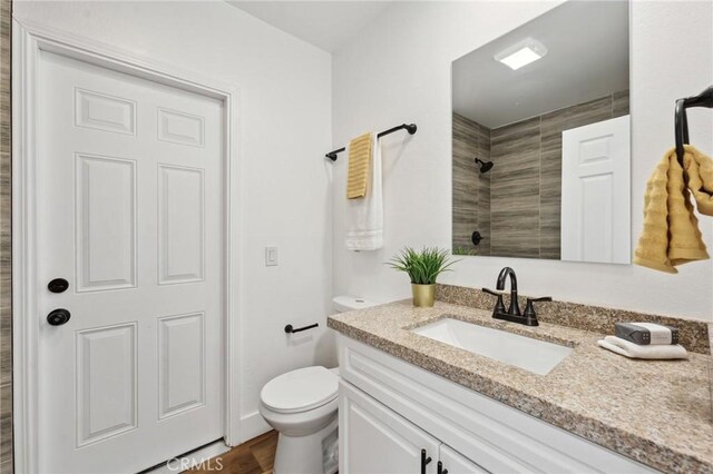 529 Manzanita Rd, Redlands, CA 92373 - bathroom featuring tiled shower, toilet, vanity, and wood finished floors