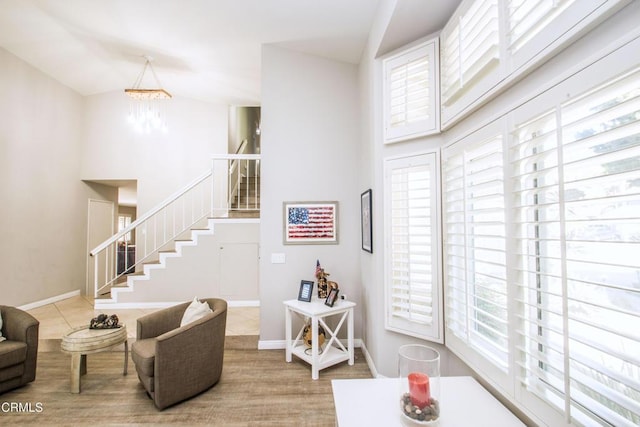 living area featuring stairs, high vaulted ceiling, a chandelier, and baseboards