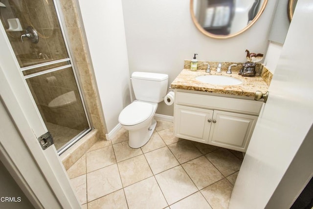 bathroom with a shower stall, toilet, tile patterned flooring, vanity, and baseboards
